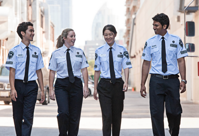 a groups of iron horse security guards walking down the street past a Canada post truck