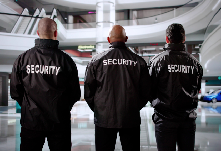 three security guards with their back looking at a mall