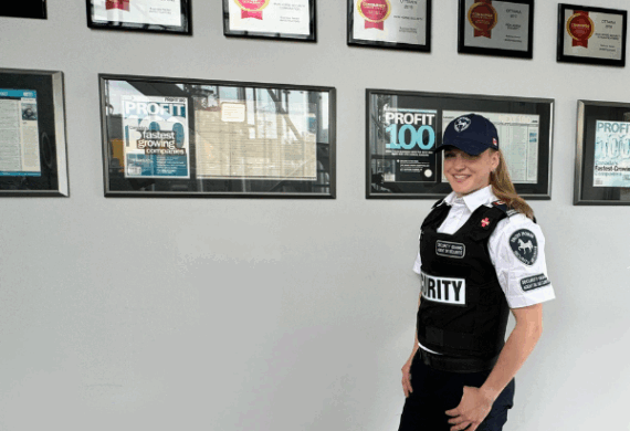 security guard officier standing in the reception of iron horse security office with several awards on the wall behind her