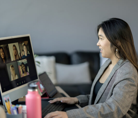 A businesswoman participates in a virtual meeting on a computer, showcasing collaborative and digital workspace concepts. The image emphasizes technology's role in fostering diverse and remote communication in modern work environments.