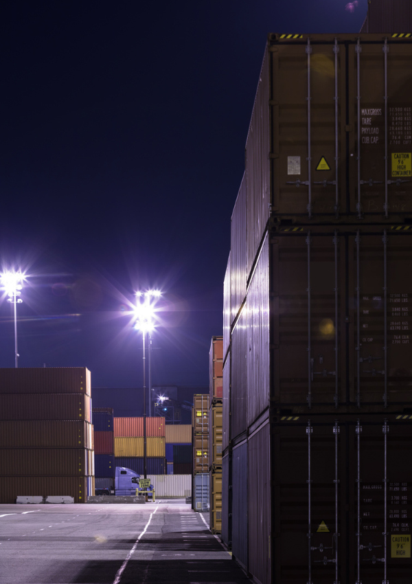 shipping yard at night with containers and a transport truck in the ditance